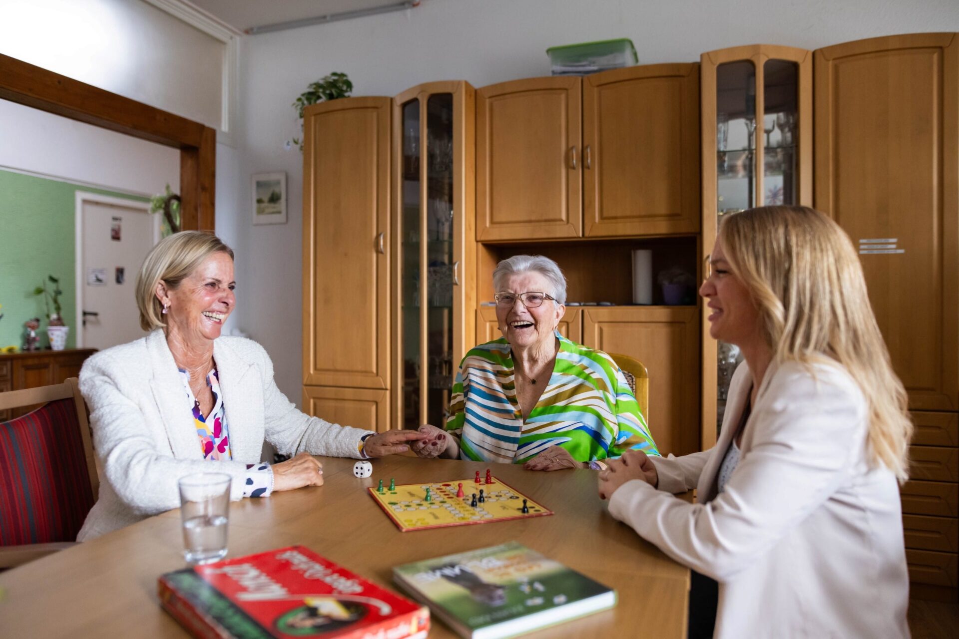 Drei Frauen spielen Brettspiel am Tisch im Rahmen der Alltagshilfe