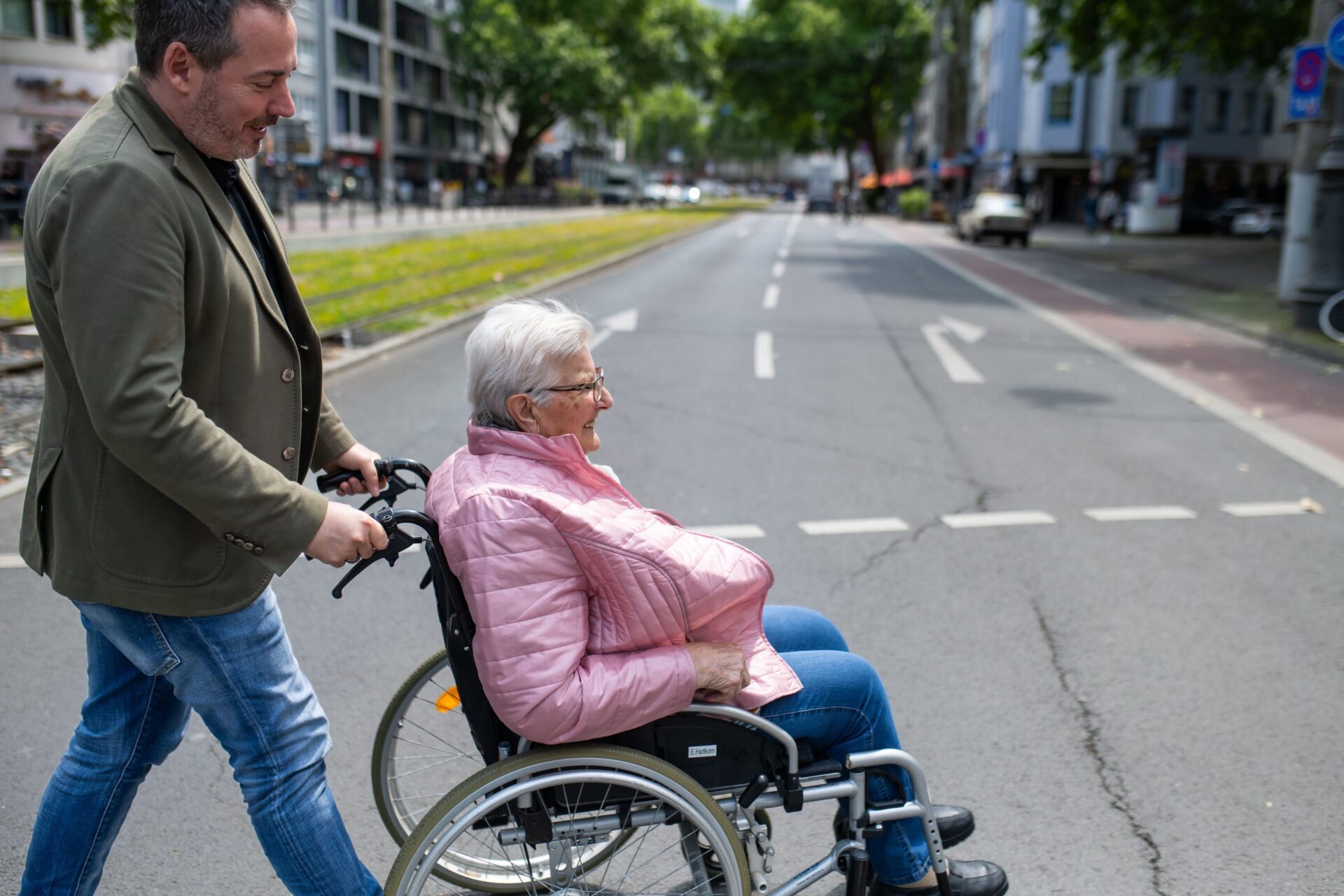 Mann schiebt Rollstuhl auf der Straße im Rahmen eines Ausflugs bei der Alltagshilfe